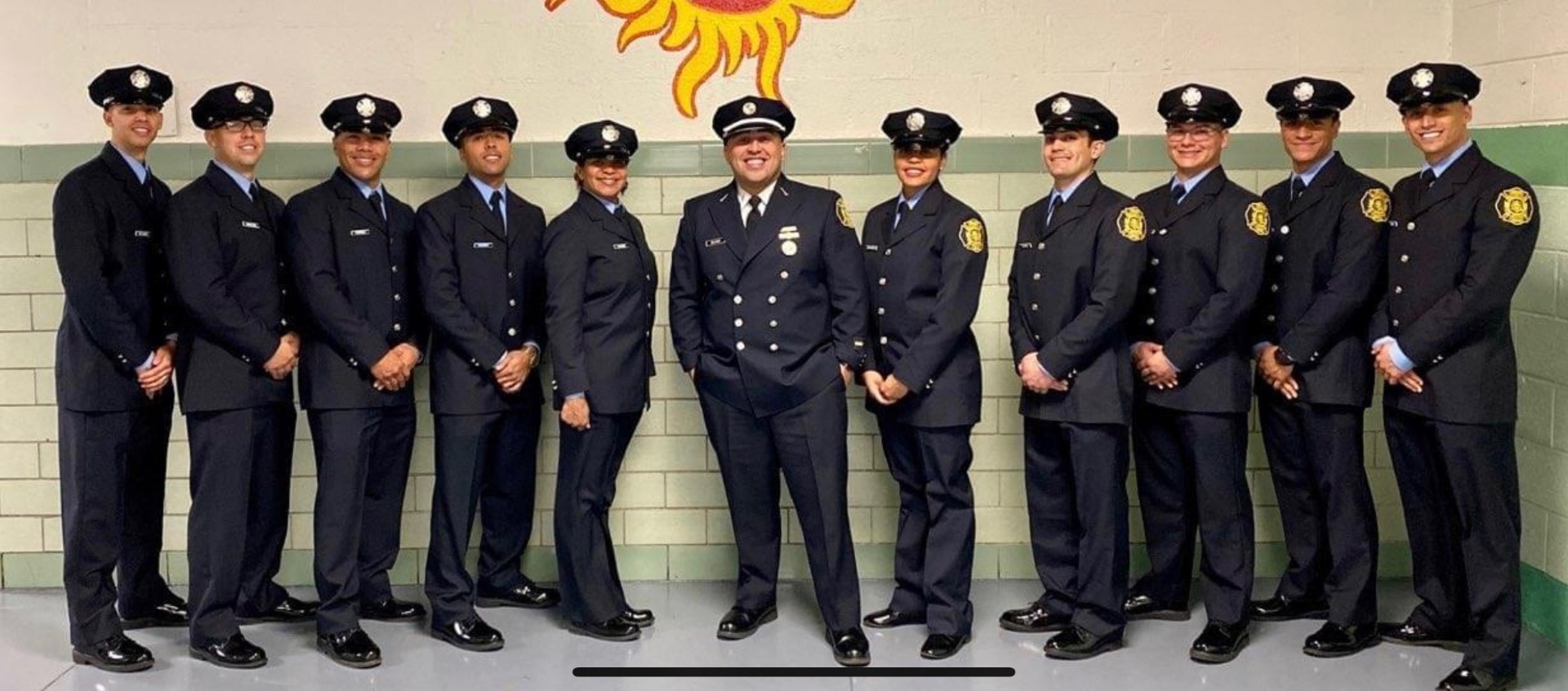 Eleven SAPFA members in dress uniform lined up at the fire academy