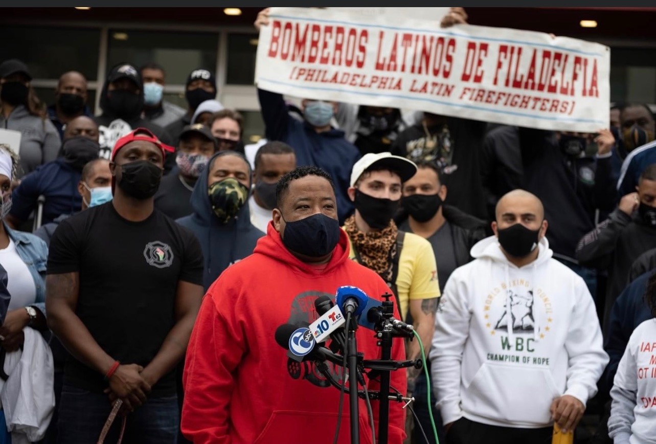SAPFA / Bomberos Latinos de Filadelfia members at a press conference with banner held overhead