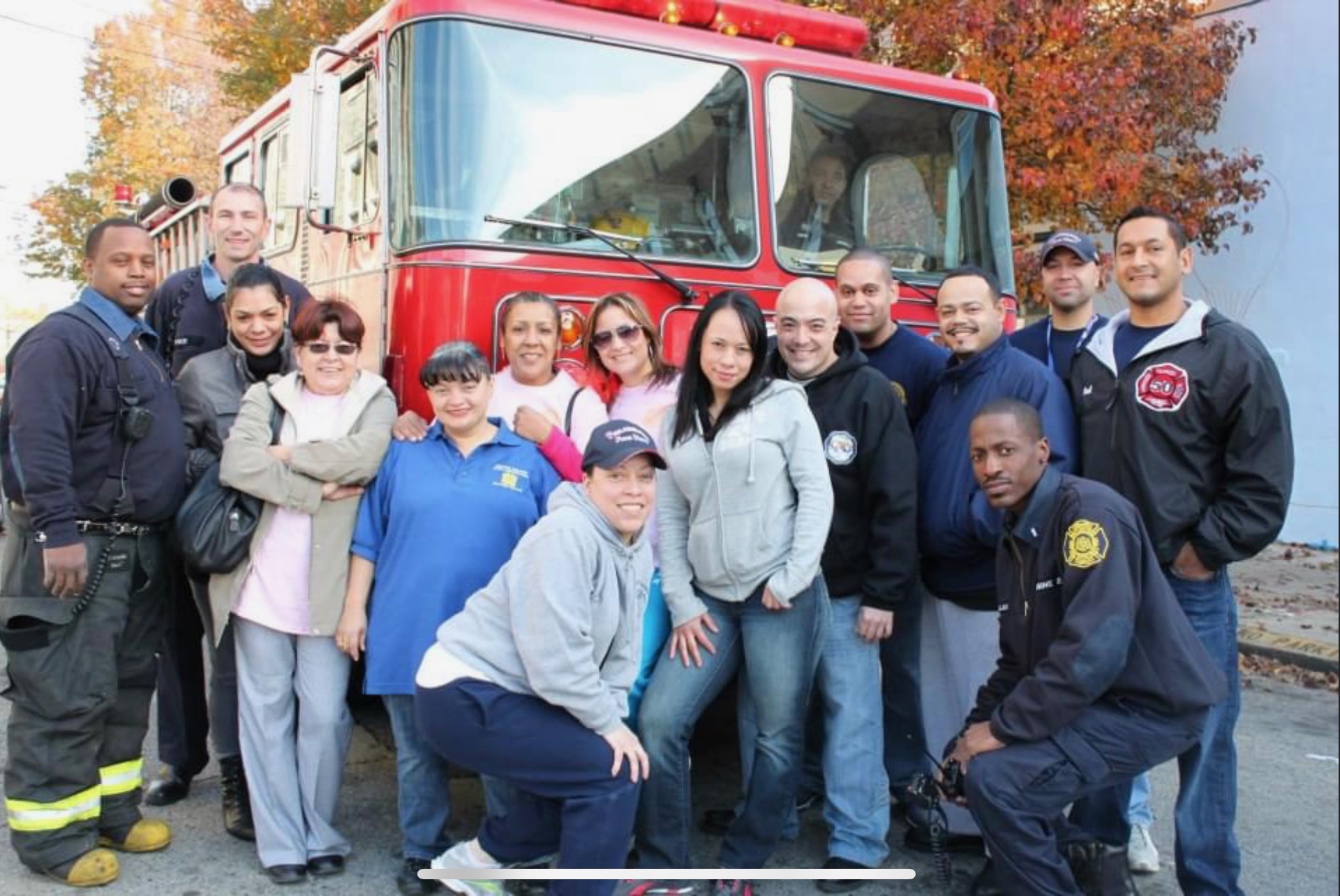 SAPFA members and community members posing in front of a fire engine on an autumn afternoon