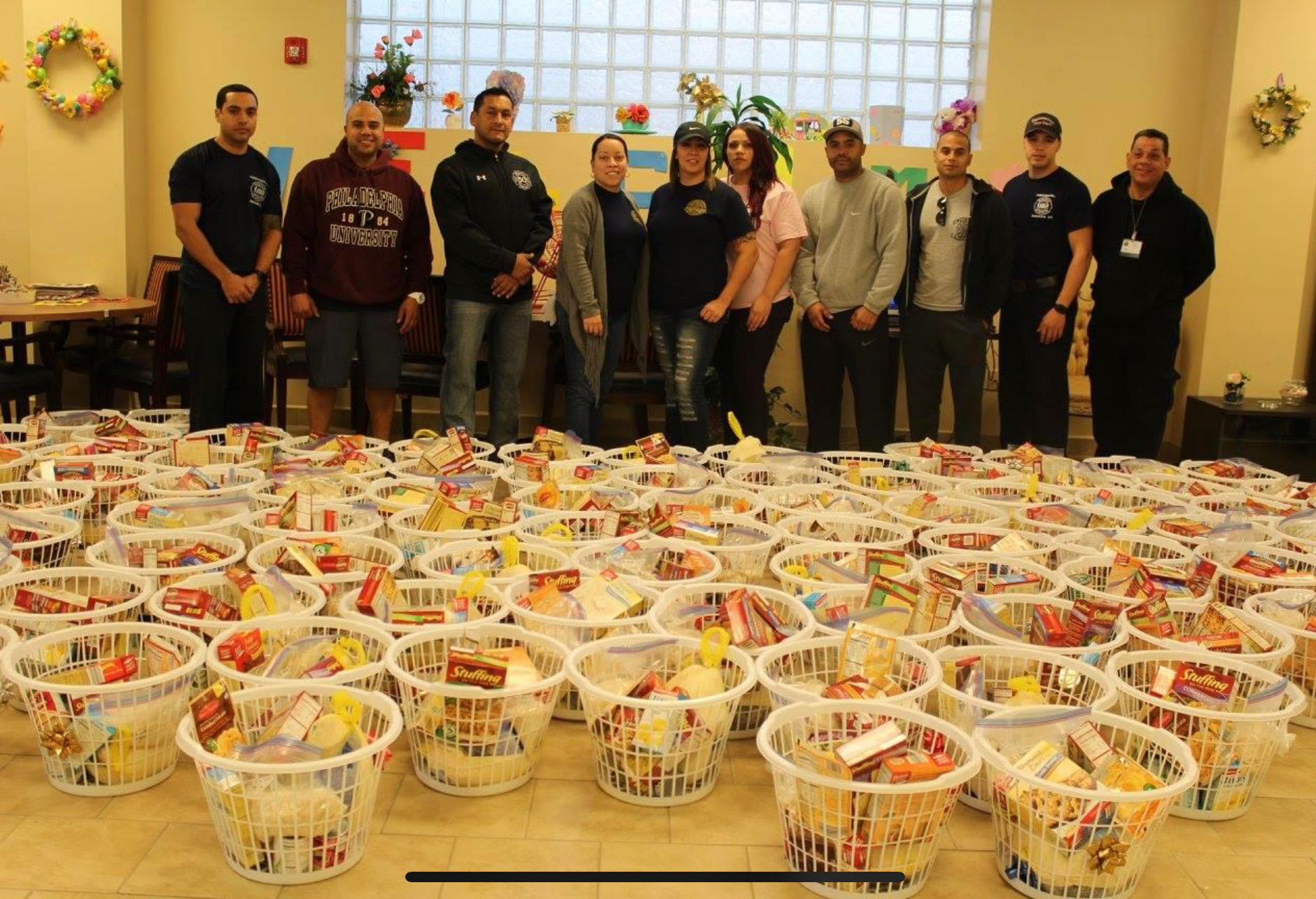 SAPFA members and volunteers standing behind dozens of prepared Thanksgiving baskets